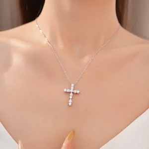 Elegante collar con colgante de cruz de plata con piedras de circonita en una modelo asiática.