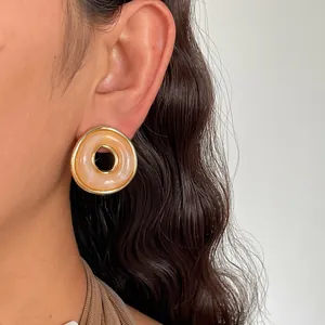 Nahaufnahme von eleganten Vintage-Ohrringen aus Acryl mit Marmor-Effekt am Ohrläppchen.