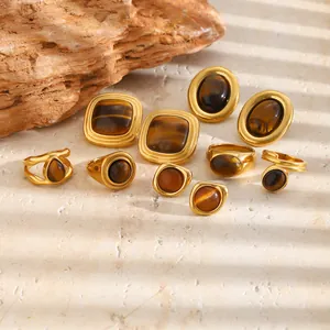 Detailopname van vintage 18k vergulde ringen en oorbellen met natuurlijke tijgeroogstenen