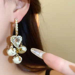 Close-up of vintage heart drop earrings with fabric-wrapped beads and rhinestones
