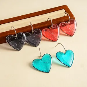 Gros plan de boucles d'oreilles cœur en résine avec texture marbrée multicolore