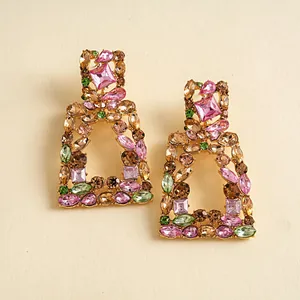 Macro-opname van vintage geometrische oorbellen met meerkleurige strass en hol ontwerp