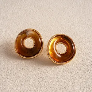 Detailansicht von Retro-Ohrsteckern aus bernsteinfarbenem Acryl mit goldenem Rahmen