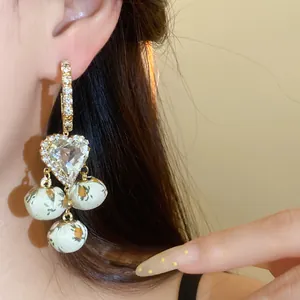 Close-up of French retro heart diamond earrings with floral fabric ball pendants.