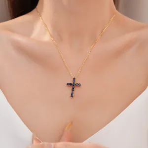 Primer plano de collar de cruz chapado en oro de 18k con circonitas azules