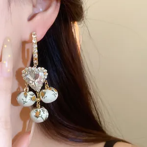 Detail shot of vintage French style earrings with rhinestone heart and floral fabric dangles