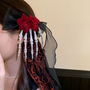 Detail view of gothic Halloween hair clip with red roses and skeleton hand fringe