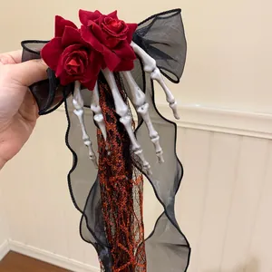 Gothic Halloween hair clip with red fabric roses, black chiffon bow and skeleton hand detail