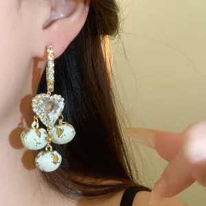 Close-up of French vintage heart earrings with sparkling rhinestones and floral fabric balls