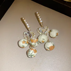 Detailed macro view of French vintage heart crystal earrings with floral fabric sphere pendants