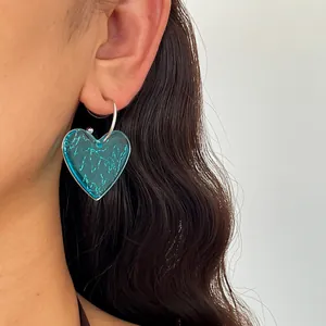 Gros plan d'une boucle d'oreille cœur en résine bleue avec texture marbrée sur un anneau