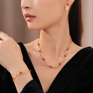 Close-up of elegant gold leaf and red flower jewelry set with sparkling rhinestones.