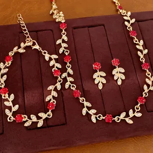 Detailed view of gold-tone floral vine jewelry set with red and white crystals