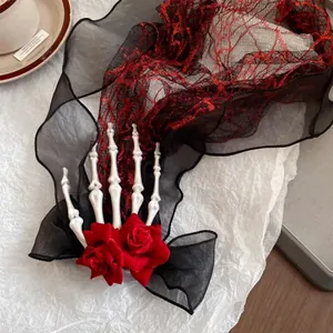 Detail of a Gothic skeleton hand hair clip with red roses and black chiffon bow decoration.