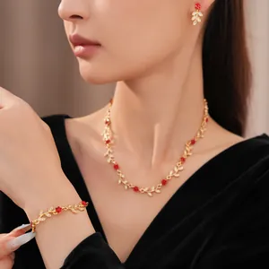 Detail view of elegant gold leaf and red flower jewelry set worn by a model.