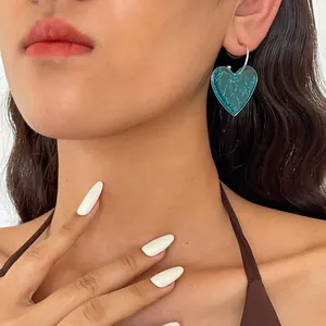 Gros plan d'une boucle d'oreille cœur en résine marbrée bleue sur un mannequin de mode