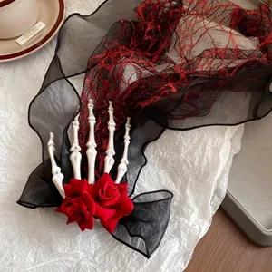 Close-up detail of dark style skeleton hand hair clip with red roses and mesh tassel