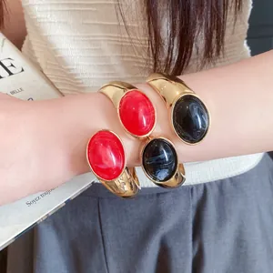 Detailed view of vintage gold oval resin open cuff bracelets in red and black tones
