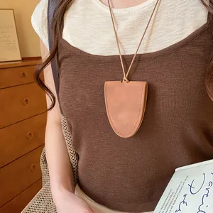 Close-up detail of a stylish brown leather glasses holder necklace worn with a brown top