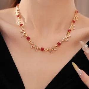 Close-up of elegant gold flower necklace with red crystals on neck