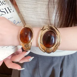 Close-up of stylish vintage gold-toned open bangles with large oval amber resin stones