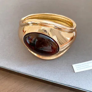 Detailed view of a vintage gold open bracelet featuring a large oval amber resin inlay