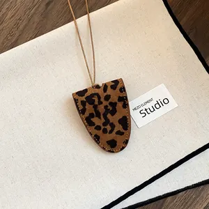 Detailed view of a leopard print glasses holder necklace with leather cord and suede texture.