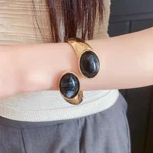 Detailed shot of an elegant gold cuff bracelet featuring two large oval black resin stones