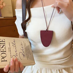Elegant leather cord necklace with a shield pendant used as a stylish glasses holder.