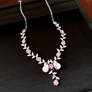 Detailed view of silver-tone floral necklace with pink crystals and teardrop pendants.