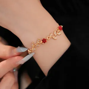 Close-up of elegant gold bracelet with red flower and leaf gems on model wrist