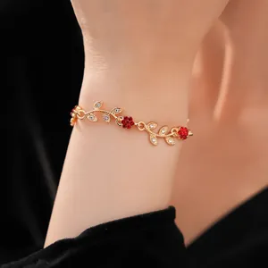 Detailed view of elegant gold vine bracelet with red crystal flowers on a wrist