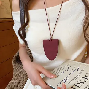 Detail of a minimalist dark red leather eyewear holder necklace worn by a model.