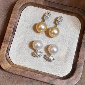 Elegant French-style gold and white pearl earrings with zircon detailing on a tray