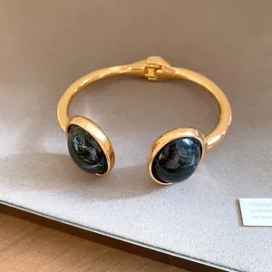 Macro view of vintage gold-tone open bangle featuring dark blue marbled resin stones