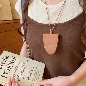 Detail view of a brown leather glasses holder necklace worn by a female model.