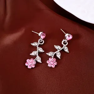 Detail view of silver-toned flower and leaf earrings with pink rhinestones