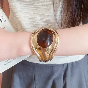 Detailed view of a vintage-style gold cuff bracelet with an oval brown resin stone