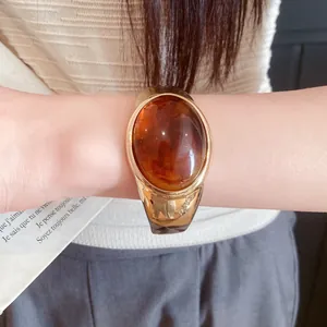 Macro detail view of a vintage oval amber resin cuff bracelet with golden metal frame