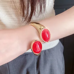 Detailed close-up view of a vintage gold open cuff bracelet with large red oval resin stones