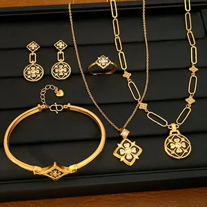 Vista detallada de un conjunto de joyas chapadas en oro con flores de esmalte negro.
