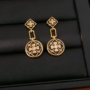 Detalle macro de los pendientes de flor chapados en oro con esmalte negro y circonitas