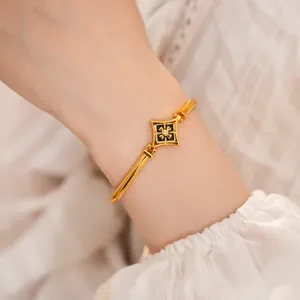 Vista detallada de un brazalete bañado en oro con esmalte negro y circonita cúbica.