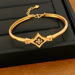 Vista detallada de un brazalete de oro con un diseño floral de esmalte negro y circón.
