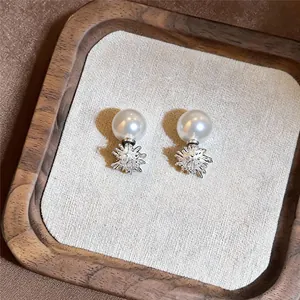 Detailweergave van elegante pareloorknopjes met zirkonia ster op een houten plateau