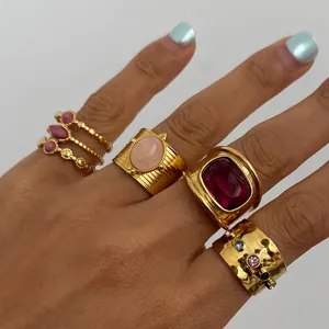 Macro view of multiple gold-plated stainless steel rings with colorful gemstones on a hand