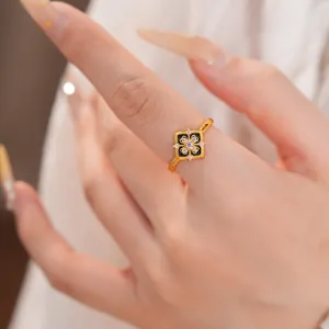 Vista detallada de un anillo de flor chapado en oro con esmalte negro y piedras circonita