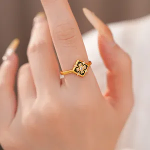 Primer plano detallado de un anillo de flor chapado en oro con esmalte negro y circón.