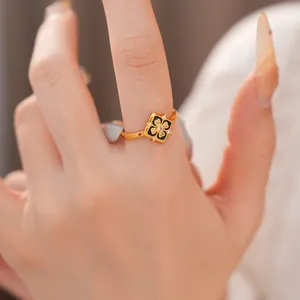 Primer plano de un anillo bañado en oro con una flor de esmalte negro y circonitas brillantes
