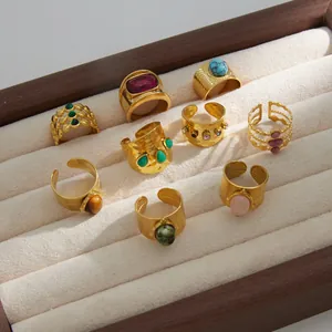 Detailed view of assorted stainless steel rings set with natural stones in a display case.